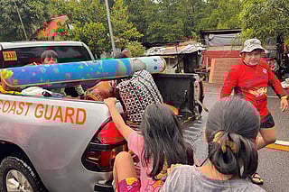 This handout photo taken on November 3, 2025 and received from the Philippine Coast Guard-Eastern Samar Station shows coast guard personnel assist in evacuating residents along coastal areas of San Julian town, Eastern Samar province, central Philippines, ahead of the landfall of Typhoon Kalmaegi.