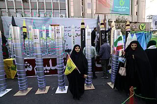 Women stand next to model missiles and a nuclear enrichment centrifuge during a rally outside the former US embassy in Tehran in a  November 4, 2025, file photo..
