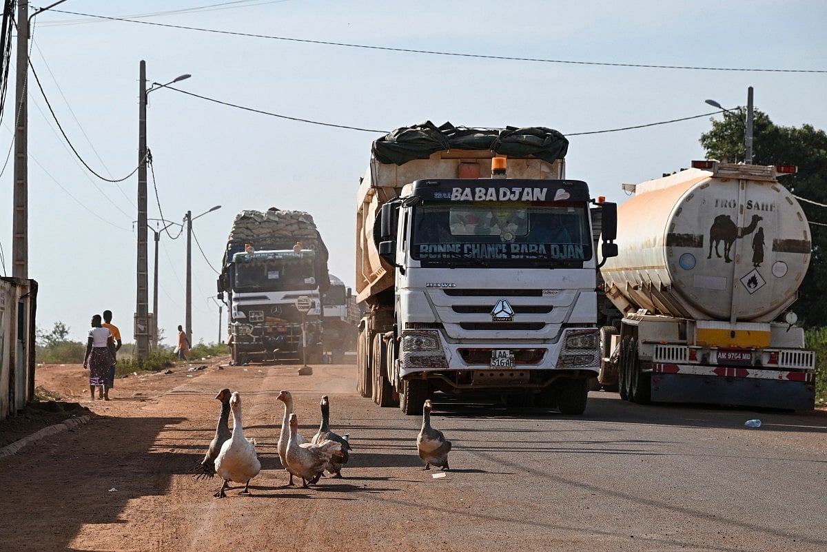 Geese walk in the road as trucks cross the border between Ivory Coast and Mali in village of Nigoun, near Tengrela, on October 31, 2025.