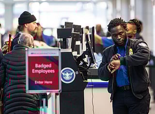 A TSA agent checks his watch while working at a security checkpoint at Ronald Reagan Washington National Airport in Arlington, Virginia on November 7, 2025.