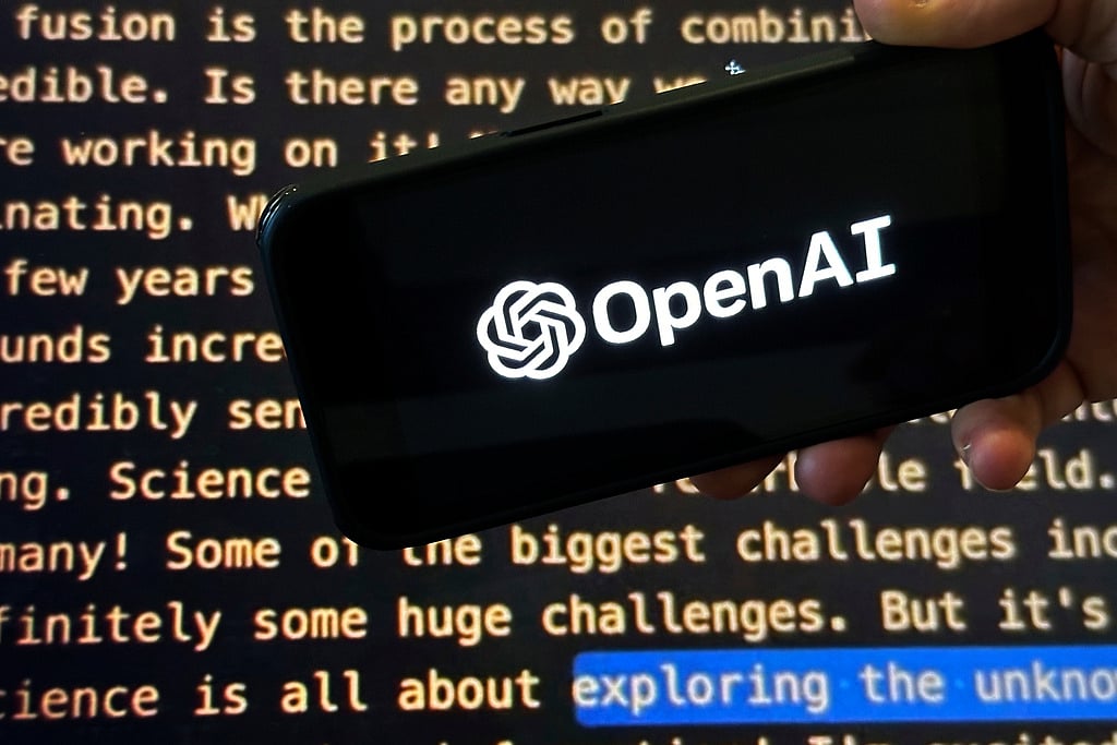 FILE - The OpenAI logo appears on a mobile phone in front of a screen showing part of the company website in this photo taken on Nov. 21, 2023 in New York. (AP Photo/Peter Morgan, File)