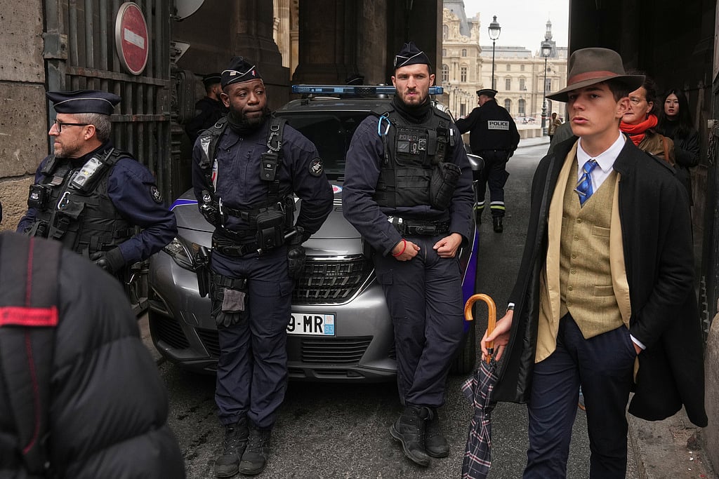 Pedro Elias Garzon Delvaux, right, walks past as police officers block an entrance to the Louvre after thieves carried out a daylight raid on French crown jewels, in Paris, October 19, 2025.