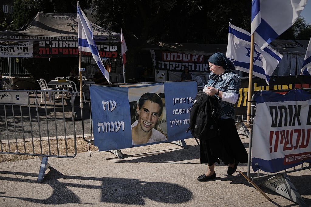 A woman walks past a photo of Hadar Goldin, an Israeli soldier killed in 2014 whose body has been held in Gaza since then, in Jerusalem, Sunday, Nov. 9, 2025.