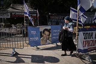 A woman walks past a photo of Hadar Goldin, an Israeli soldier killed in 2014 whose body has been held in Gaza since then, in Jerusalem, Sunday, Nov. 9, 2025.  