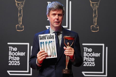 Hungarian-British author David Szalay poses for photographers with the trophy after winning the Booker Prize 2025 for his book 'Flesh' during a ceremony at Old Billingsgate in London, Monday, Nov. 10, 2025.