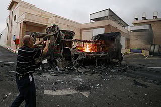 A Palestinian man uses a mobile phone to record a burning truck after an Israeli settlers attack in the village of Beit Lid, east of Tulkarm in the occupied West Bank on November 11, 2025.