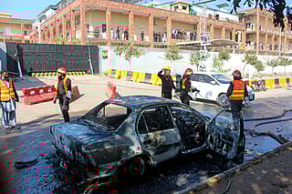 Firefighters douse a car at the suicide blast site in Islamabad on November 11, 2025.