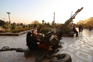 Iranian women sit on an anti-aircraft gun displayed during an exhibition showcasing missile and drone achievements in Tehran. File photo taken on November 12, 2025.