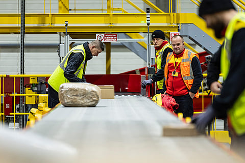 Employees put parcels on a line at a DHL warehouse in Lesquin, near Lille, on November 12, 2025.