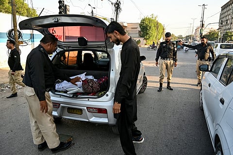 A policeman searches a vehicle along a road in Karachi on November 12, 2025, a day after a suicide bombing blast in Islamabad.