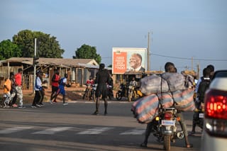 Pedestrians cross a street in Boundiali, northern Ivory Coast, on November 1, 2025 where Ivorians truck drivers refuse to go to Mali due to militant attacks.