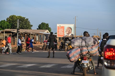 Pedestrians cross a street in Boundiali, northern Ivory Coast, on November 1, 2025 where Ivorians truck drivers refuse to go to Mali due to militant attacks.