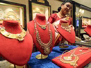 A saleswoman with a gold necklace at a jewellery shop (Photo/ANI)