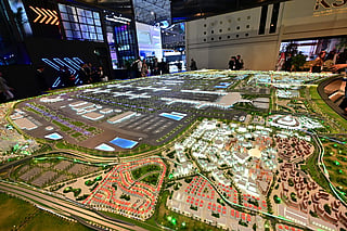 People look at the model of the new Al-Maktoum International Airport during the Dubai Airshow 2025 in Dubai on November 17, 2025.