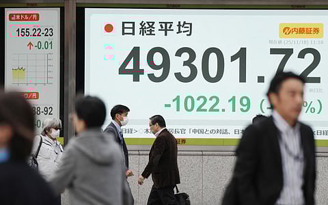 Pedestrians walk past an electronic quotation board displaying numbers of the Nikkei Stock Average on the Tokyo Stock Exchange during a morning session in Tokyo on November 18, 2025. File photo