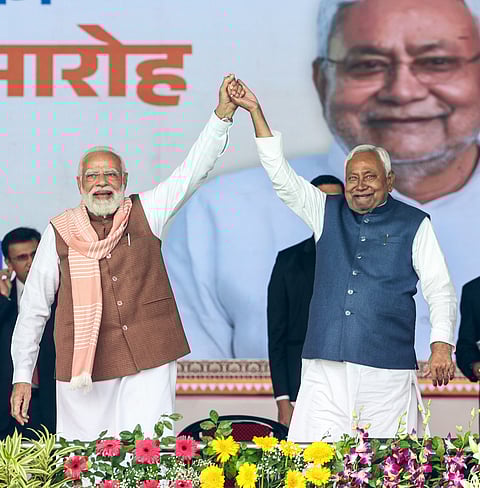 Prime Minister Narendra Modi hand-in-hand with JDU Chief Nitish Kumar during oath taking ceremony, in Patna on Thursday.  