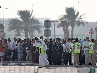 Police officers give instructions to people queueing for the 2025 Dubai Airshow at Al Maktoum International Airport after an Indian fighter jet crashed during a flying display in Dubai on November 21, 2025. 