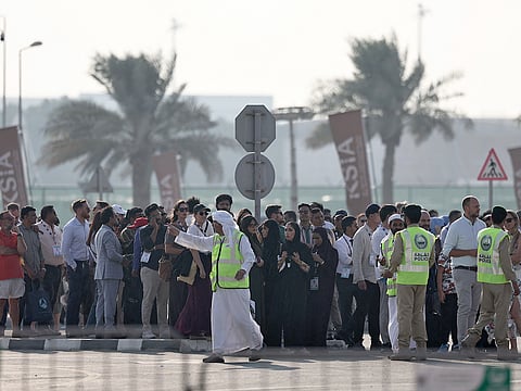 Police officers give instructions to people queueing for the 2025 Dubai Airshow at Al Maktoum International Airport after an Indian fighter jet crashed during a flying display in Dubai on November 21, 2025. 