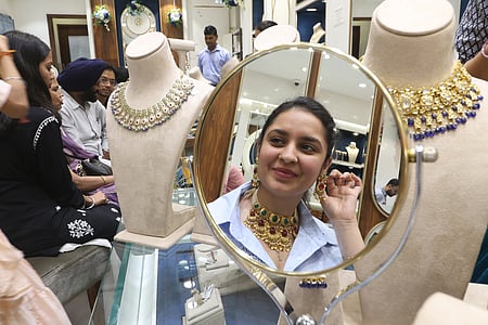 A woman looks at her reflection while trying on gold jewellery in a Dubai shop.