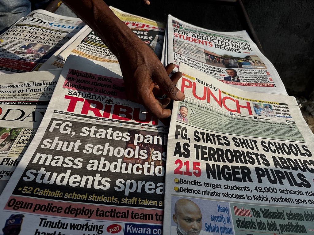 A street vendor in Lagos displays local newspapers with headlines on gunmen abducting schoolchildren and staff of the St. Mary's Catholic Primary and Secondary School in Papiri community in Nigeria, Saturday, Nov. 22, 2025. (AP Photo/Sunday Alamba )