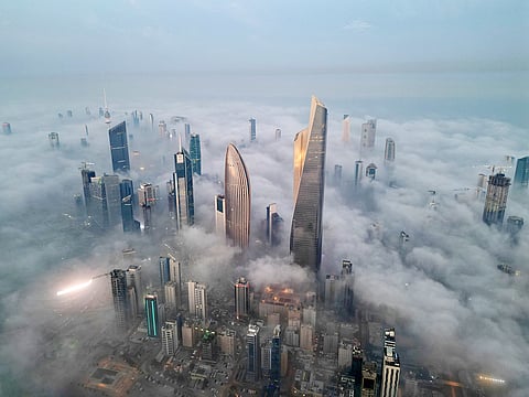 This aerial photograph shows skyscrapers enveloped in early morning fog in Kuwait City on November 9, 2025. 