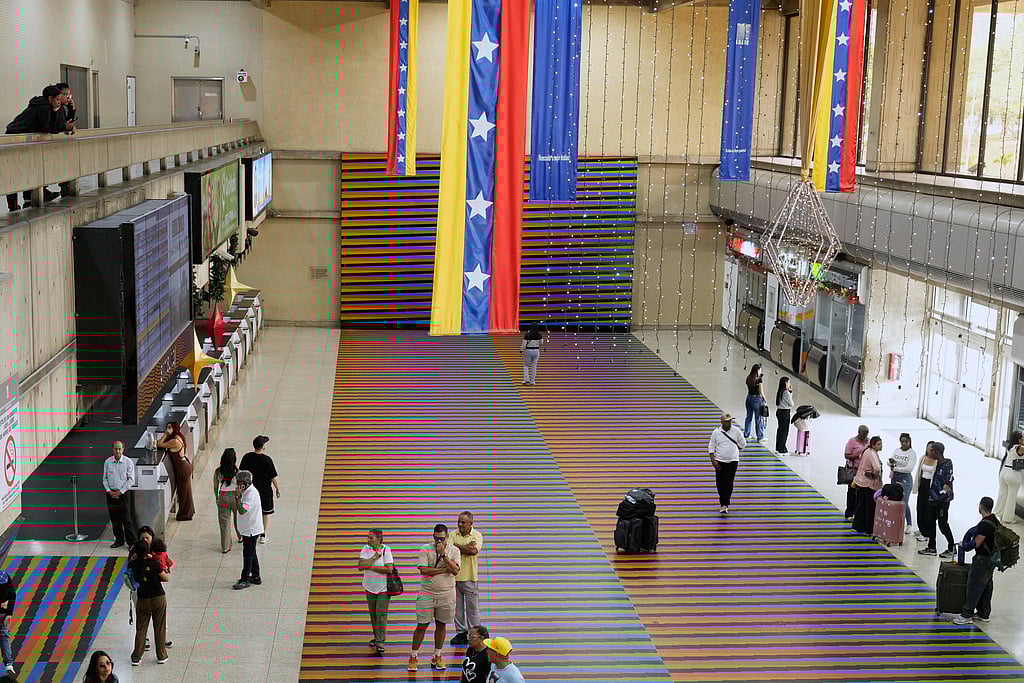 Travelers wait in the main hall of the Simon Bolivar Maiquetia International Airport in Maiquetia, Venezuela, Sunday, Nov. 13, 2025, after several international airlines canceled flights following a warning from the U.S. Federal Aviation Administration about a hazardous situation in Venezuelan airspace.  