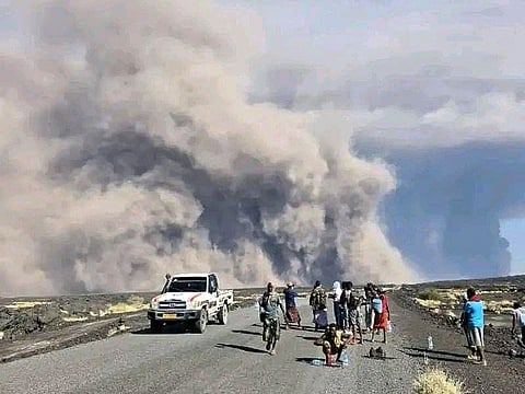 People watch ash billow from the first time eruption of the Hayli Gubbi Volcano in Ethiopia's Afar region Sunday.