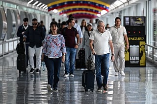 Passengers walk after arriving at Maiquetia Simon Bolivar International Airport in Caracas on November 24, 2025.