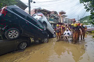 Rescuers carry a resident past cars washed away by floods at the height of Typhoon Kalmaegi at a subdivision of Cebu City in the central Philippines on November 4, 2025.