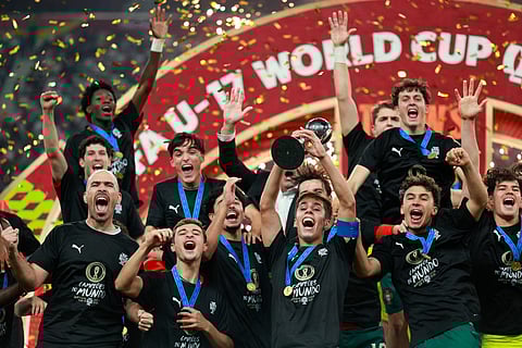 Portugal's players celebrate with the trophy on the podium after the FIFA U17 World Cup final football match between Portugal and Austria at Khalifa International Stadium in Al-Rayyan on November 27, 2025.