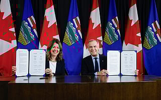 Prime Minister Mark Carney, right, signs an MOU with Alberta Premier Danielle Smith in Calgary, Alta., Thursday, Nov. 27, 2025. (Jeff McIntosh /The Canadian Press via AP)