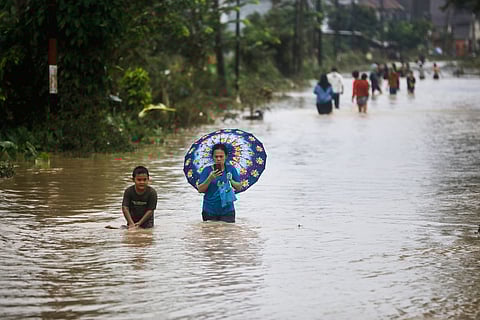 People wade through the water at a flooded street in Medan, North Sumatra, Indonesia, Thursday, Nov. 27, 2025. 