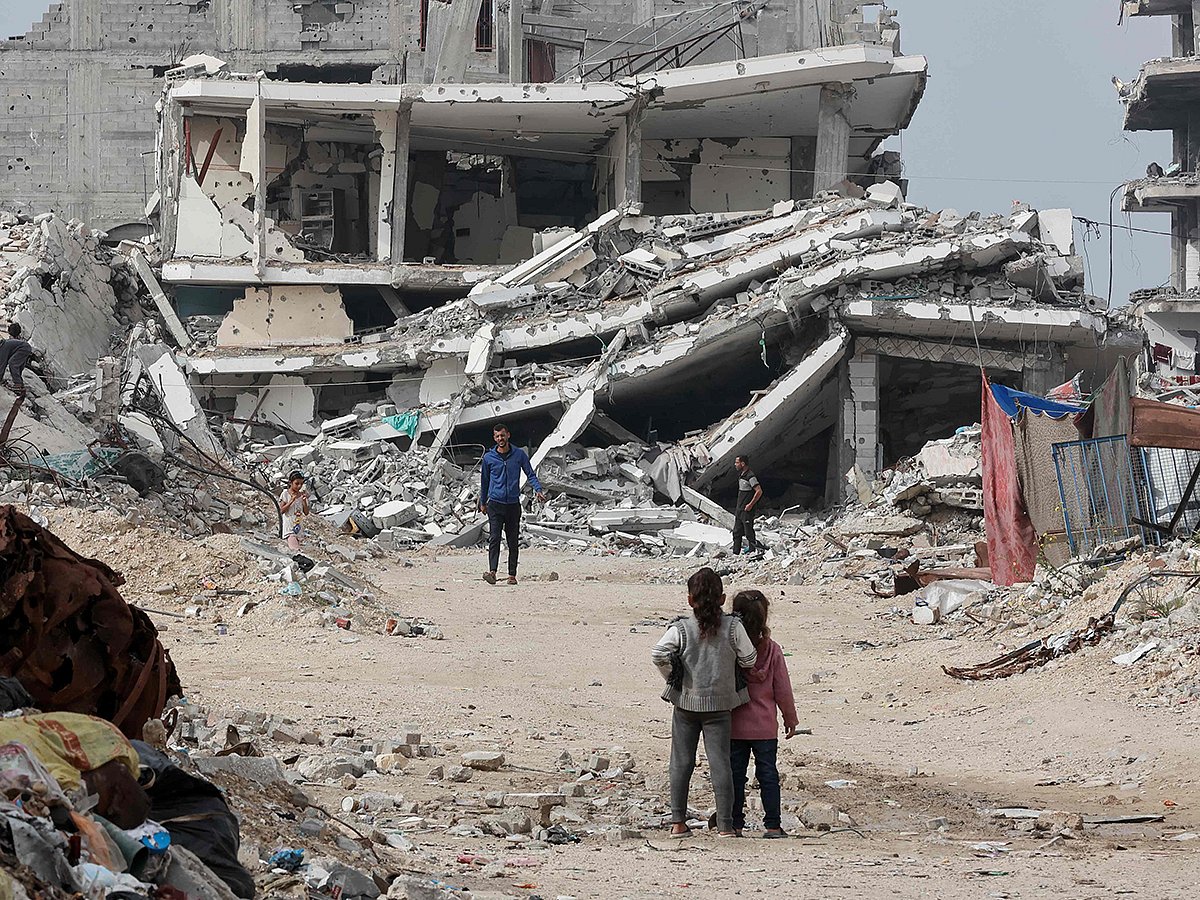 Displaced Palestinians walk past destroyed buildings in the Tel Al Hawa neighbourhood, in the southern part of Gaza City, on November 29, 2025. 