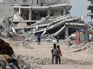 Displaced Palestinians walk past destroyed buildings in the Tel Al Hawa neighbourhood, in the southern part of Gaza City, on November 29, 2025. 