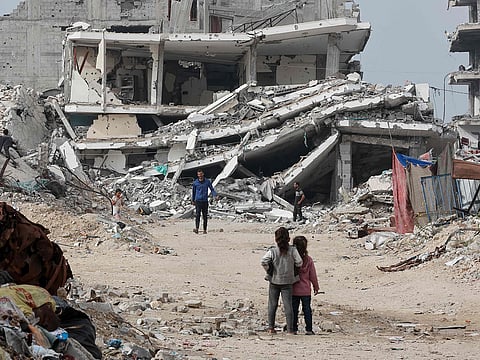 Displaced Palestinians walk past destroyed buildings in the Tel Al Hawa neighbourhood, in the southern part of Gaza City, on November 29, 2025. 