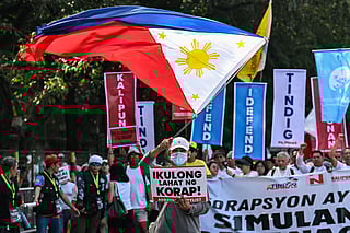 A protester with a Philippine flag marches with a placard that reads "jail all the corrupt" during an anti-corruption rally along Epifanio de los Santos Avenue, or EDSA, in Quezon City, Metro Manila on November 30, 2025.