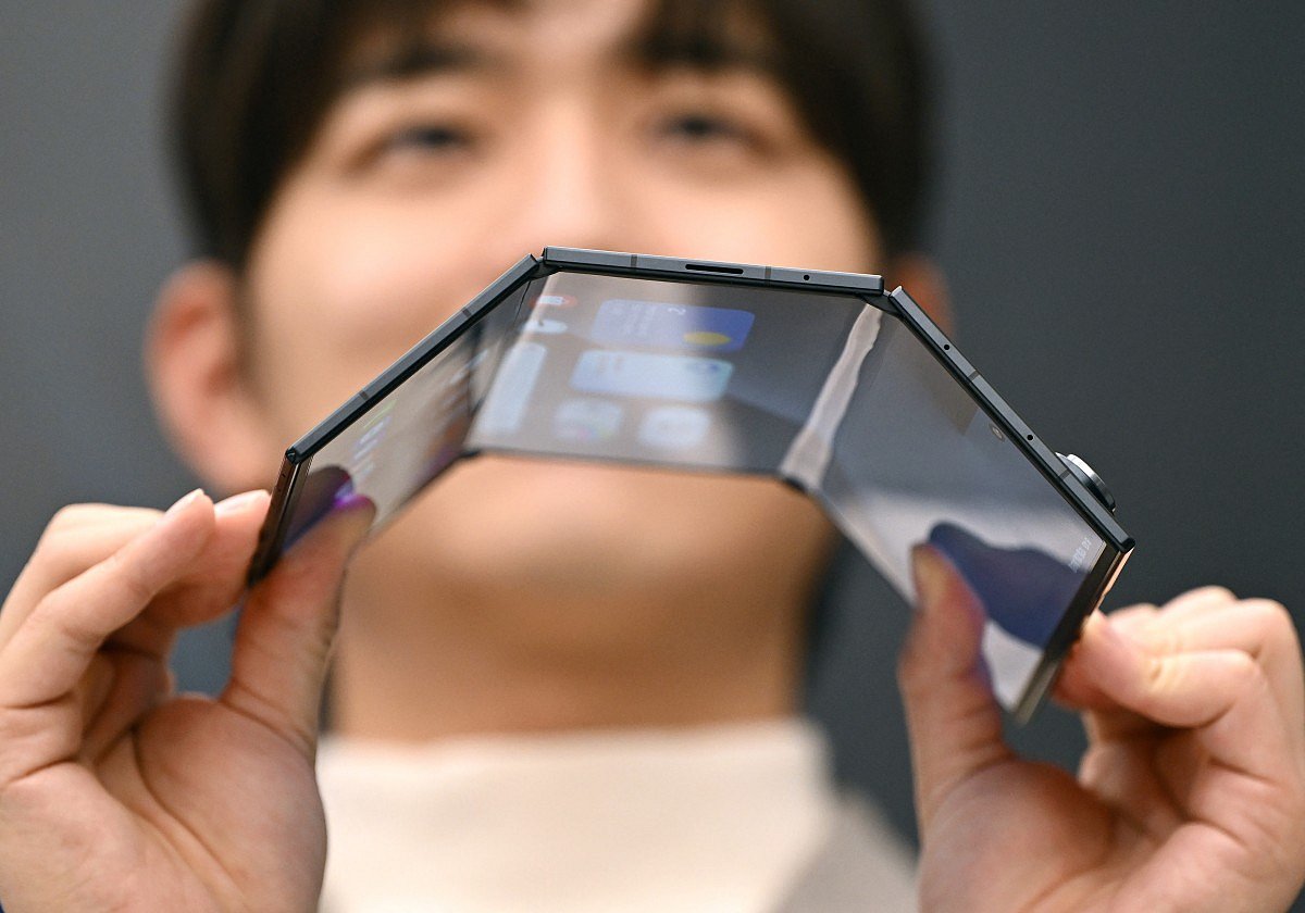 A promoter shows a Samsung Galaxy Z TriFold smartphone during a launch event at a Samsung store in Seoul on December 2, 2025.