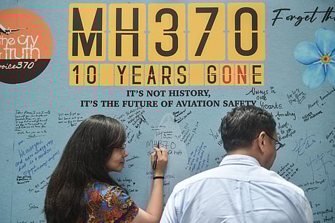 A woman writes a message during an event held by relatives of missing passengers and supporters to mark the 10th anniversary of the disappearance of Malaysia Airlines flight MH370, in Subang Jaya on March 3, 2024.