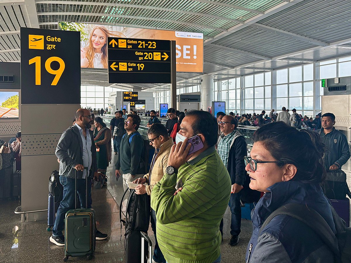 Passengers wait outside the Indira Gandhi International Airport in New Delhi, India, as several Indigo Airlines flights were either cancelled or delayed, on Thursday, December 4, 2025.