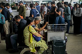 Passengers wait near the IndiGo Airlines kiosk at the Chennai International Airport in Chennai on December 5, 2025.