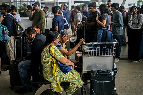 Passengers wait near the IndiGo Airlines kiosk at the Chennai International Airport in Chennai on December 5, 2025.