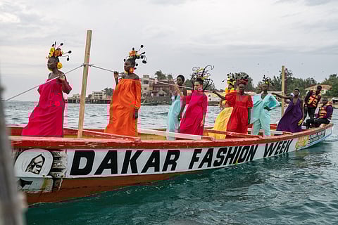 Models, wearing designs by Senegalese fashion designer Adama Paris, ride on a pirogue during the final show of the Dakar Fashion Week in Ngor Bay, Dakar, Senegal.
