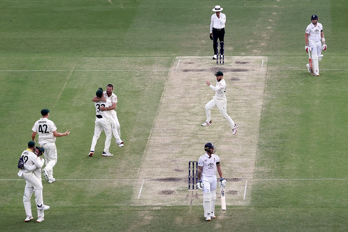 Australia’s wicketkeeper Alex Carey (L) celebrates with captain Steve Smith after taking a catch to dismiss England’s captain Ben Stokes (C) on day four of the second Ashes cricket Test match between Australia and England at The Gabba in Brisbane on December 7, 2025.