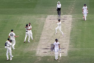 Australia’s wicketkeeper Alex Carey (L) celebrates with captain Steve Smith after taking a catch to dismiss England’s captain Ben Stokes (C) on day four of the second Ashes cricket Test match between Australia and England at The Gabba in Brisbane on December 7, 2025.