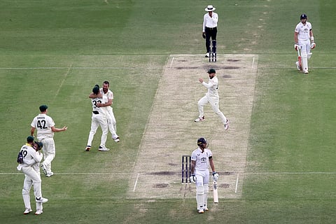 Australia’s wicketkeeper Alex Carey (L) celebrates with captain Steve Smith after taking a catch to dismiss England’s captain Ben Stokes (C) on day four of the second Ashes cricket Test match between Australia and England at The Gabba in Brisbane on December 7, 2025.