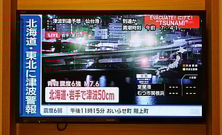 A tsunami warning flashes over live footage of a waterfront area, on a television screen in Sapporo, in Japan’s northern Hokkaido prefecture on December 9, 2025.