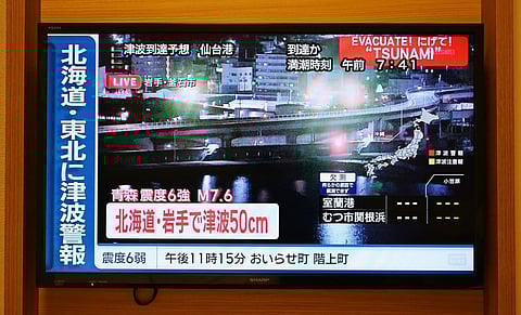 A tsunami warning flashes over live footage of a waterfront area, on a television screen in Sapporo, in Japan’s northern Hokkaido prefecture on December 9, 2025.