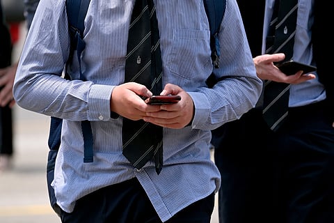 A schoolboy looks at his phone in Melbourne on November 27, 2024 as Australia looks to ban children under 16 from social media with claims social media platforms have been tarnished by cyberbullying, the spread of illegal content, and election-meddling claims.