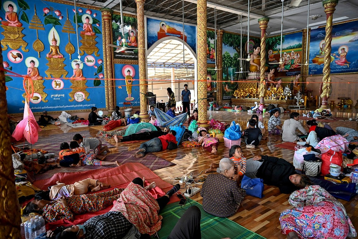 Residents rest inside a temple after they evacuated following clashes along the Cambodia-Thailand border, in Siem Reap province on December 9, 2025.