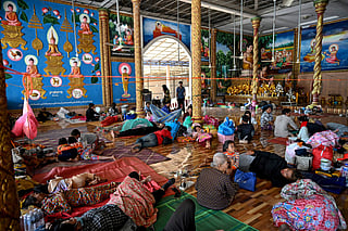 Residents rest inside a temple after they evacuated following clashes along the Cambodia-Thailand border, in Siem Reap province on December 9, 2025.